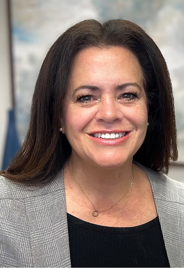 Deana Arseneau, co-author of the ebook, smiling in a grey blazer.